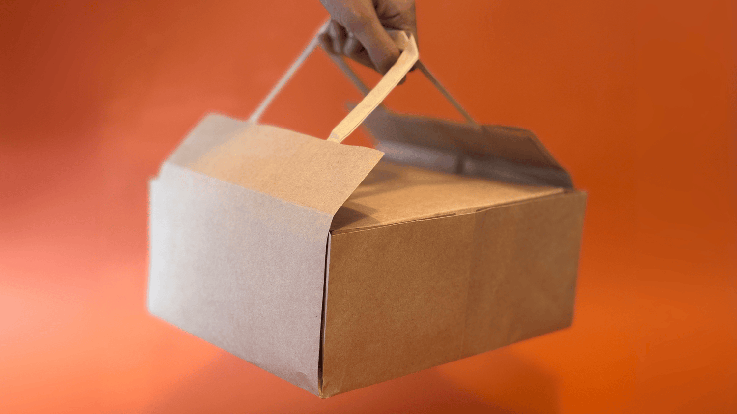 Brown paper bag with a handle against an orange background