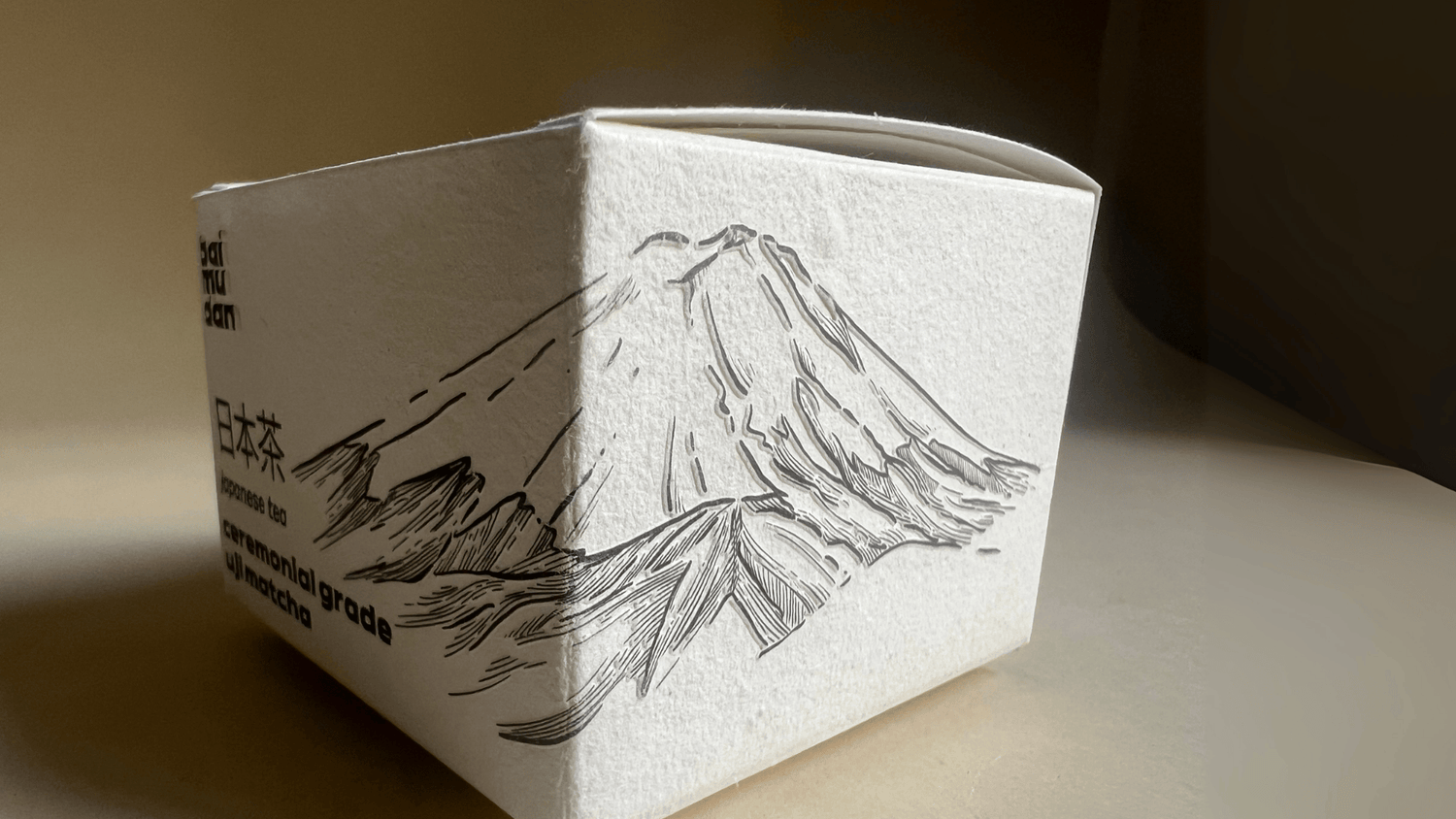 White tea box with mountain design and text on a beige background