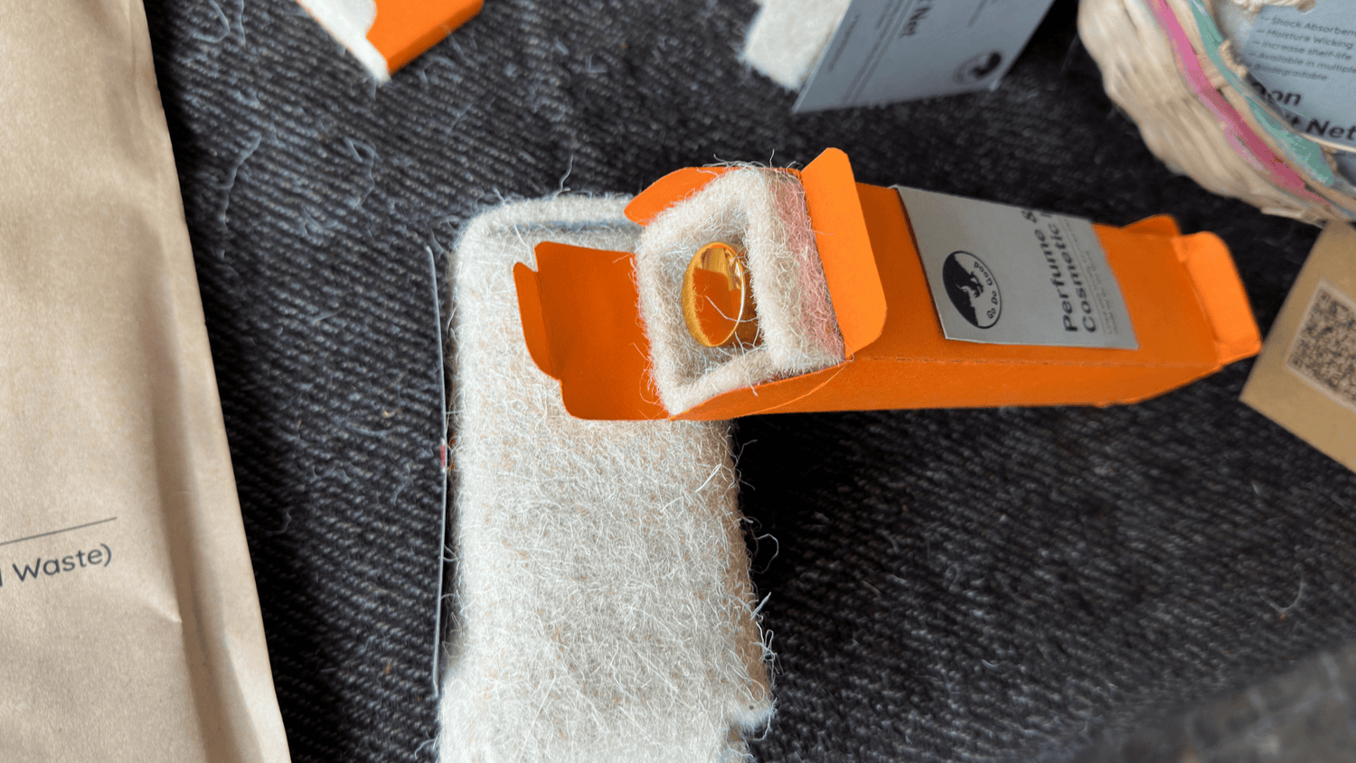 Orange and white plastic clip on a textured surface with a label attached.