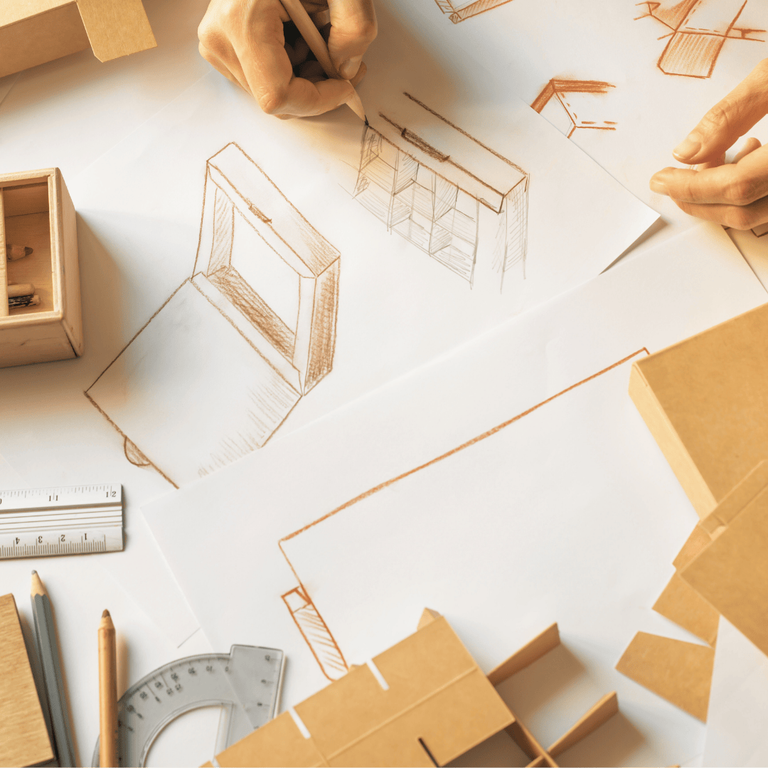 Design process with architectural drawings and cardboard models on a table.